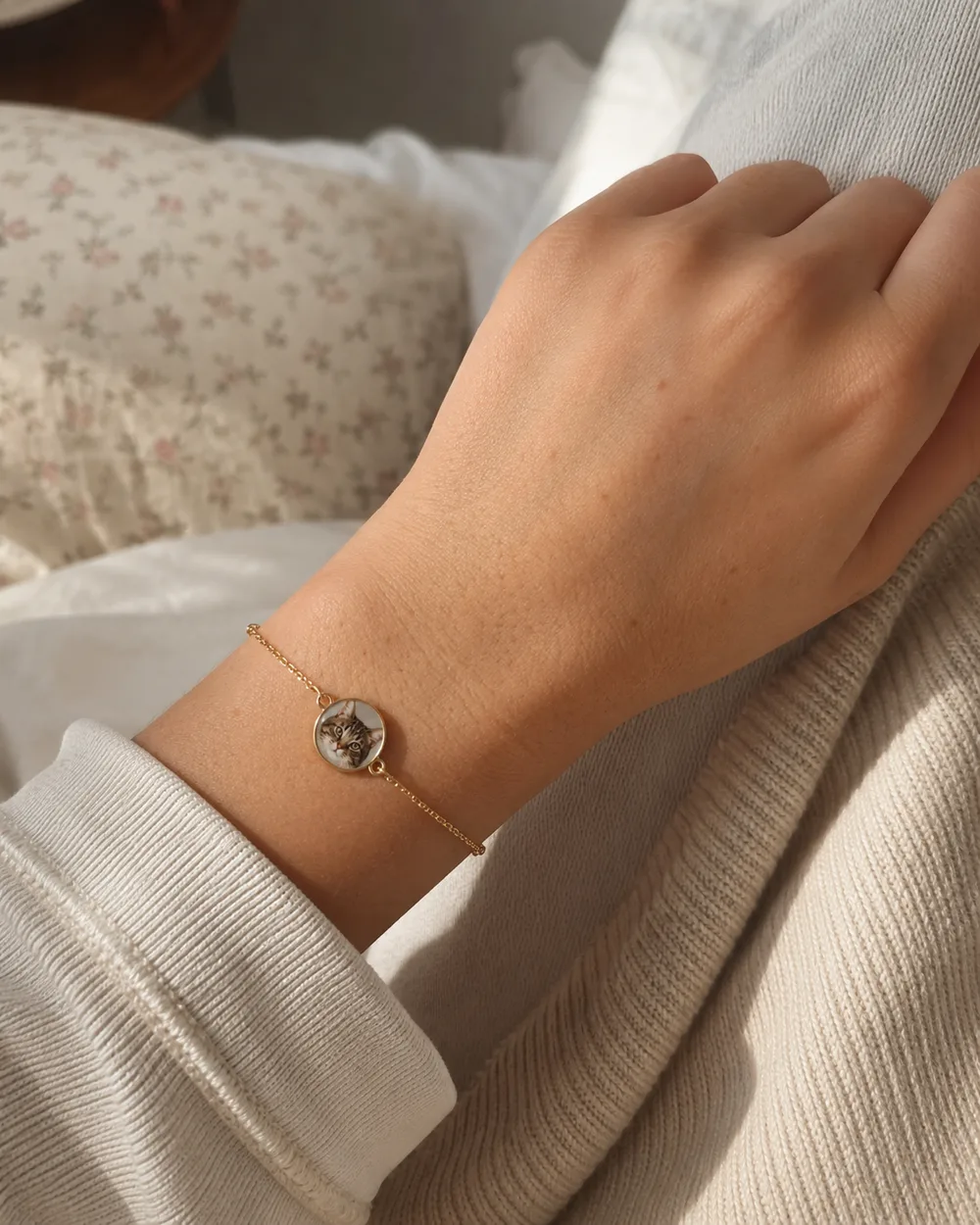 Gold bracelet with a round charm featuring a tabby cat portrait, worn on a wrist