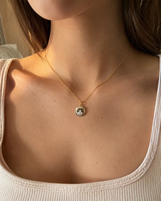 María wearing a gold necklace with a round pendant featuring Luna’s cat portrait